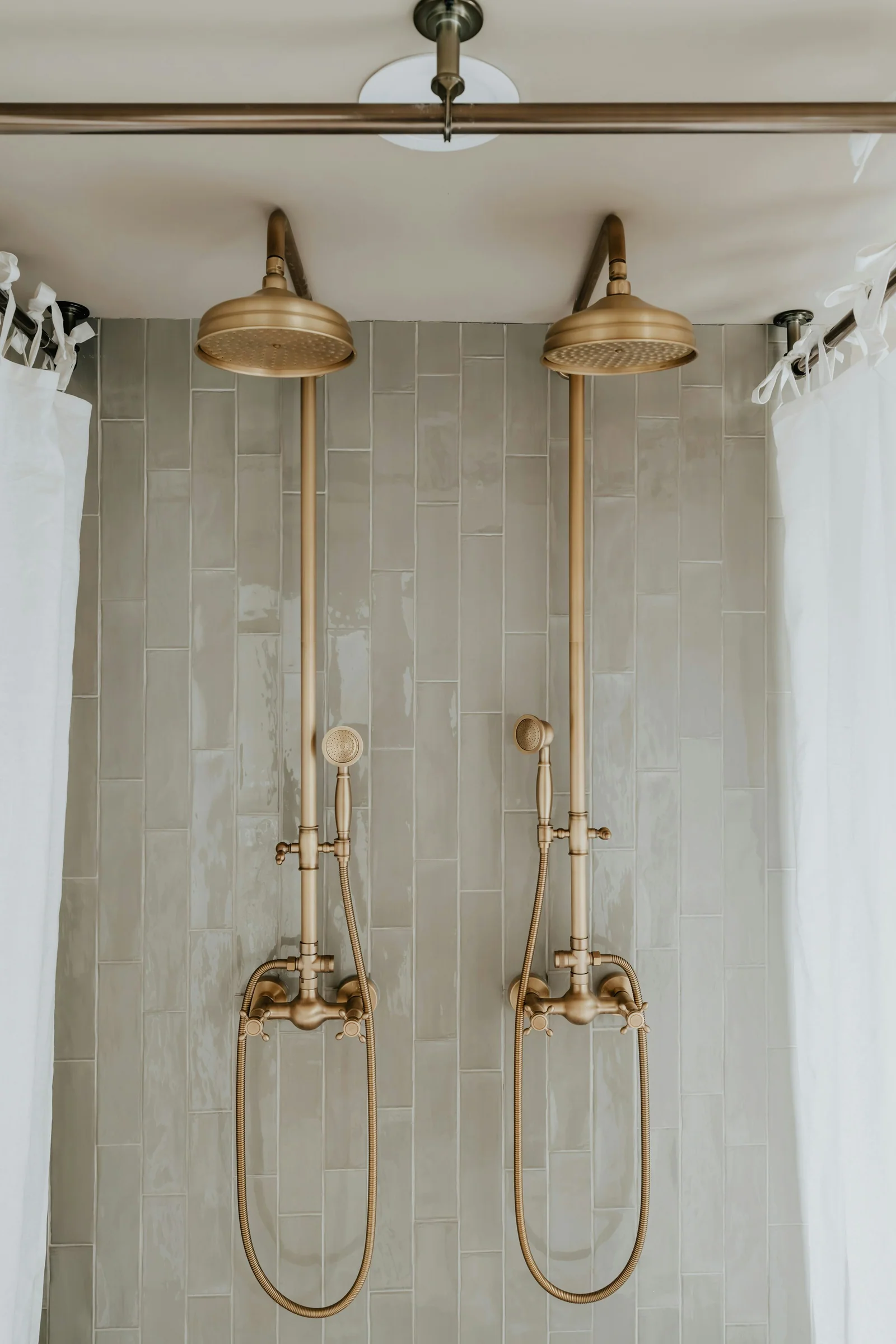 Double shower with brass fixtures and tall stone tile