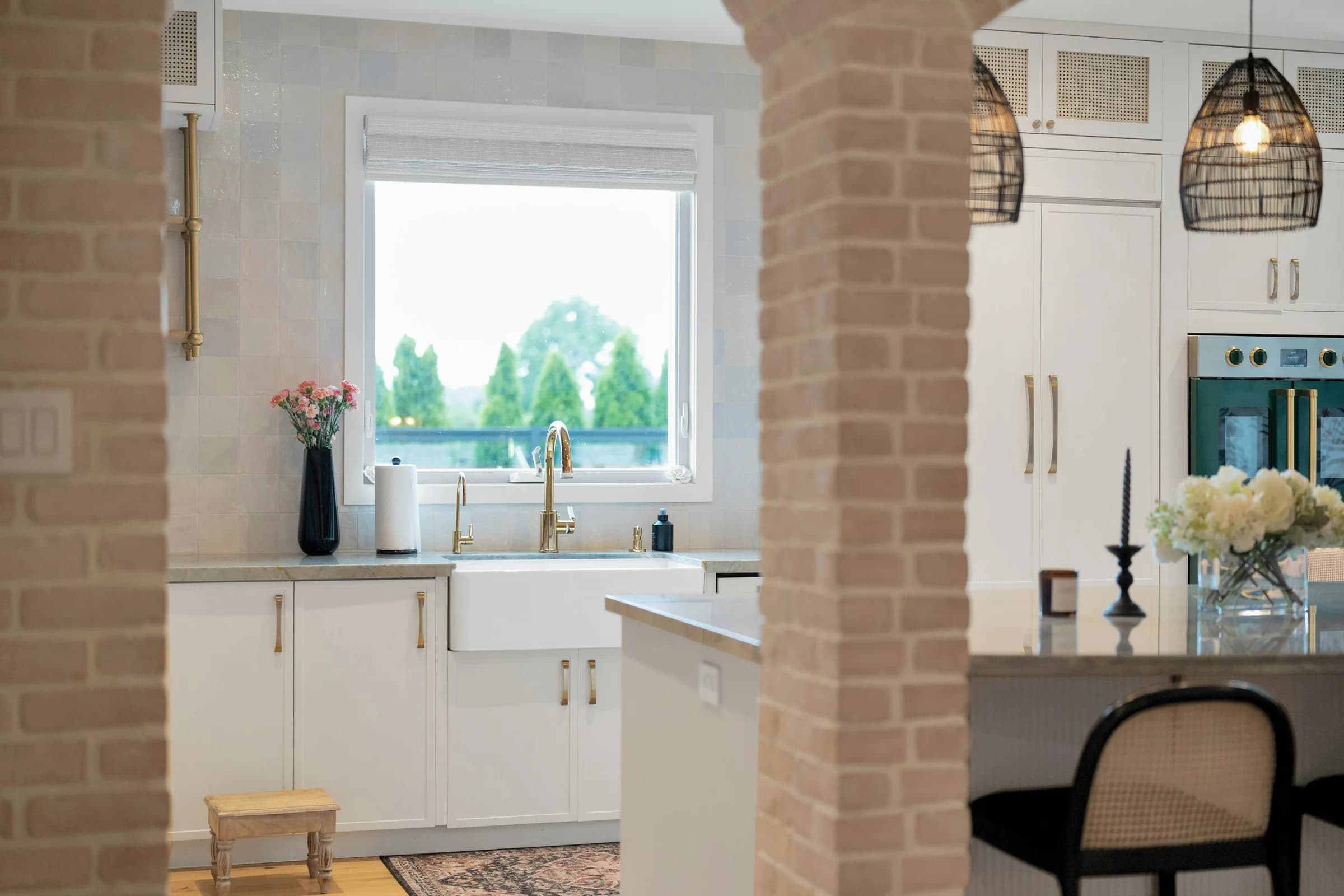 White kitchen framed by exposed brick arches