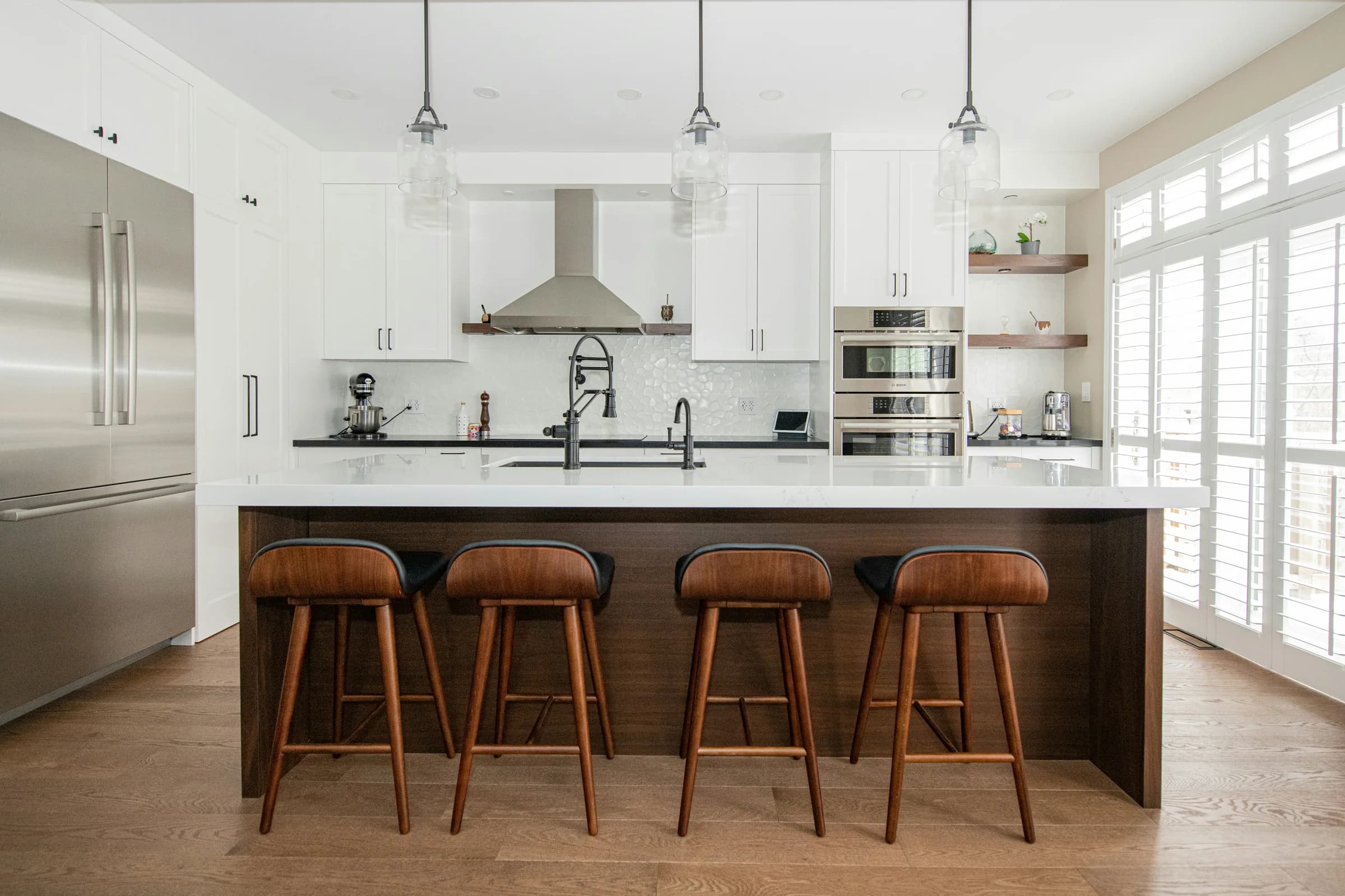 Bright white kitchen with a walnut island and leather stools