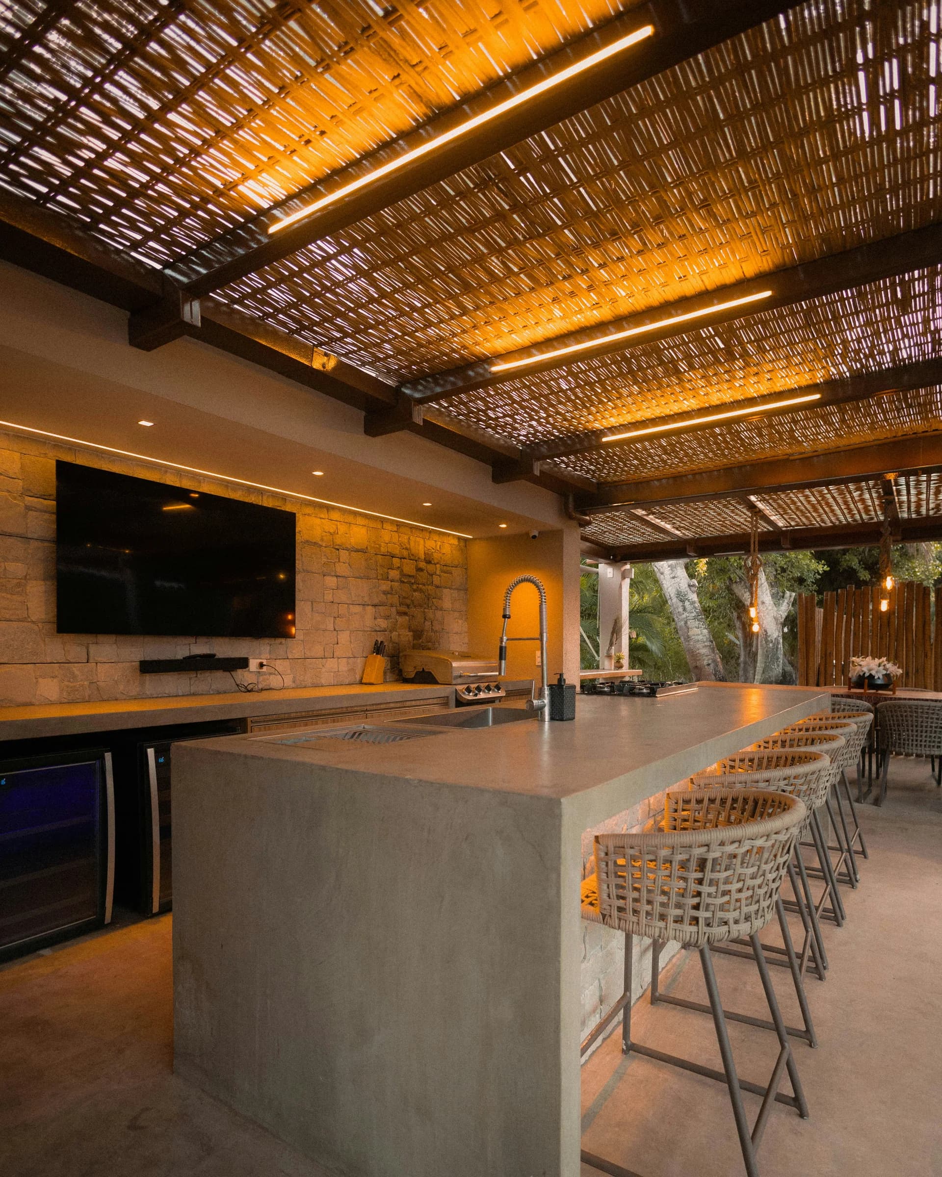Covered outdoor kitchen and bar beneath a timber pergola