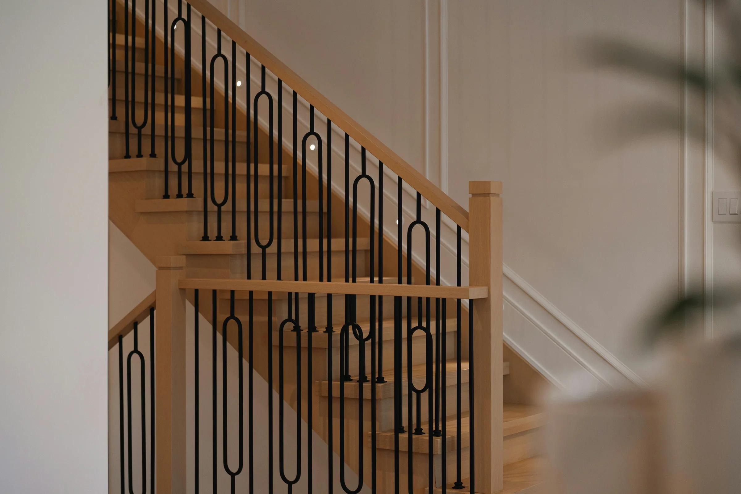 Curved oak staircase with slender black iron balusters