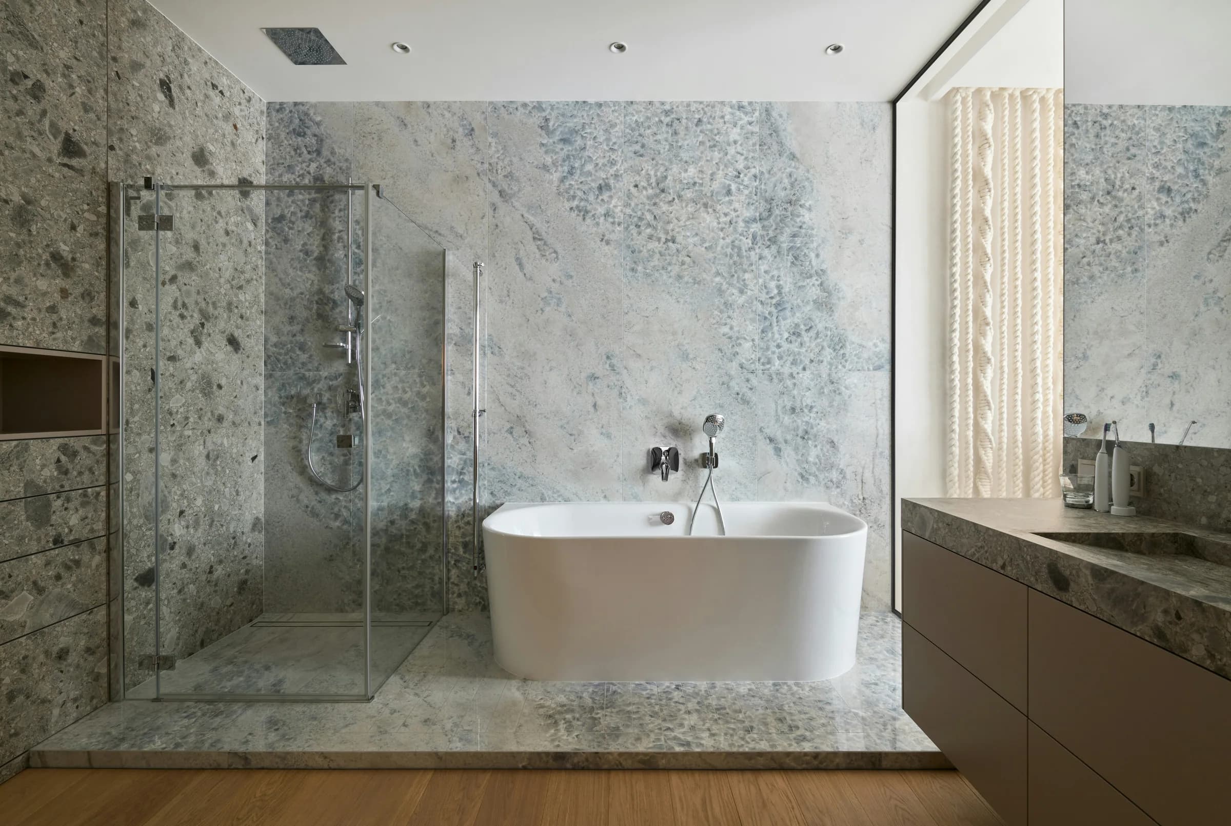 Marble-lined bathroom with a freestanding tub and glass shower