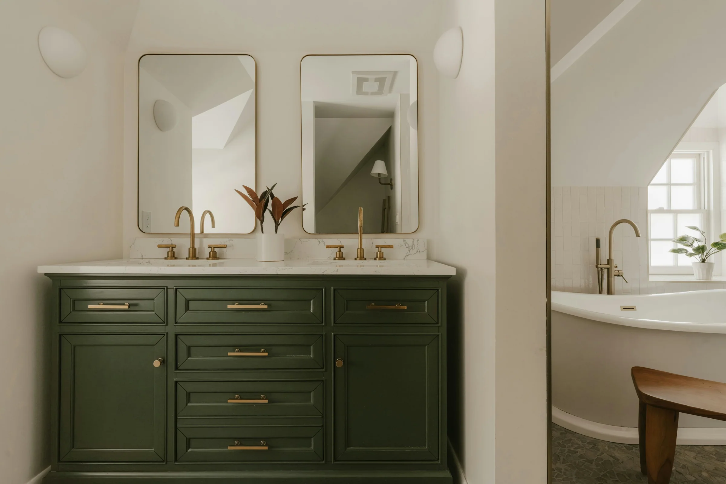 Olive green double vanity with brass fittings and a freestanding bath