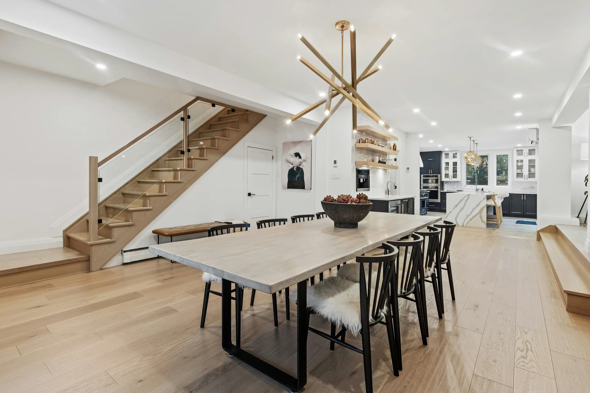 Oak dining table beside an open staircase and white cabinetry