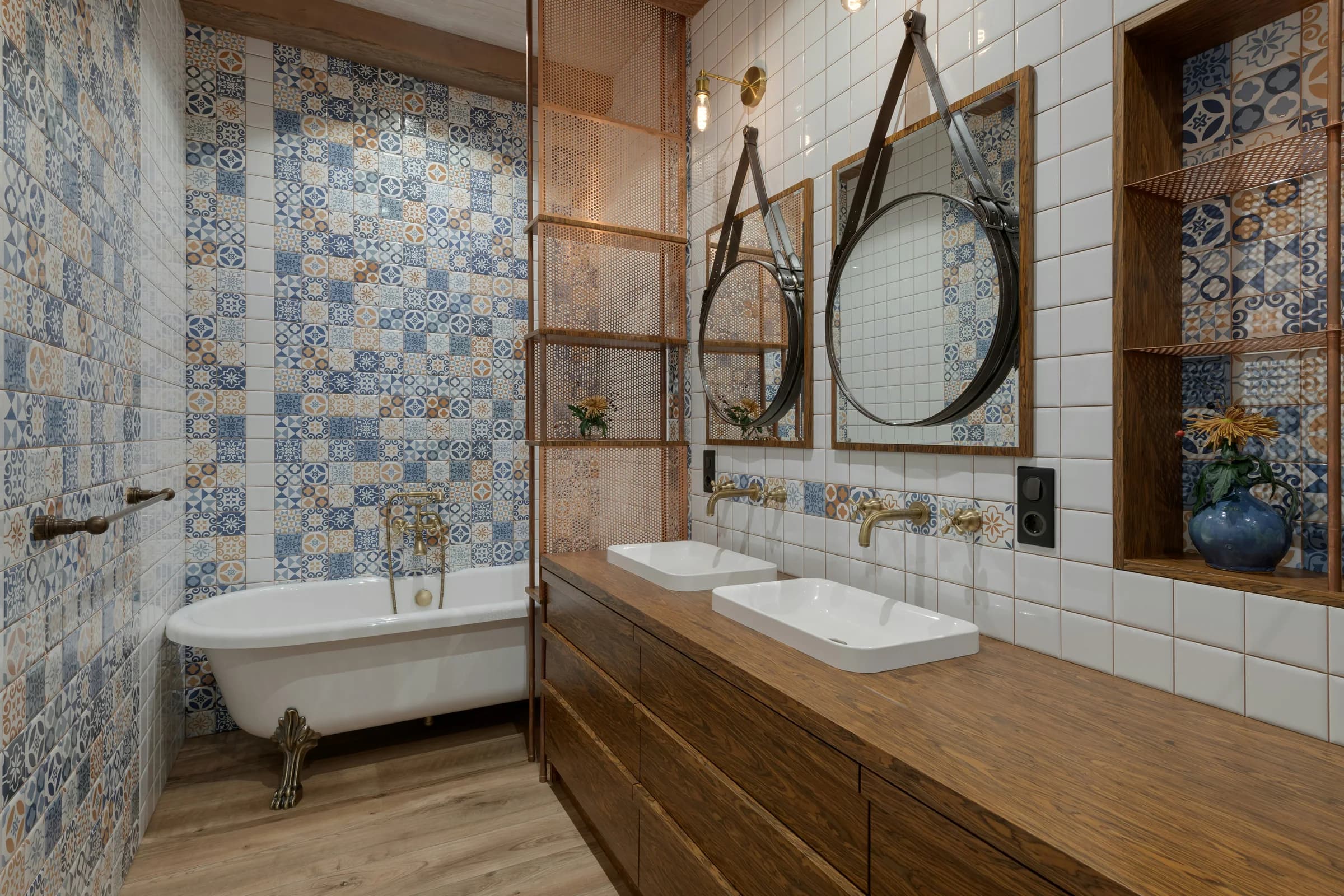 Bathroom with blue patterned tile, round mirrors, and timber cabinetry
