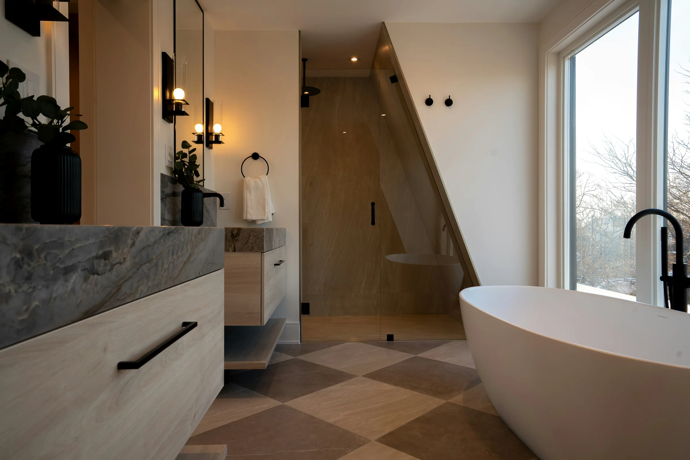 Stone bathroom with a freestanding soaking tub beside a large window