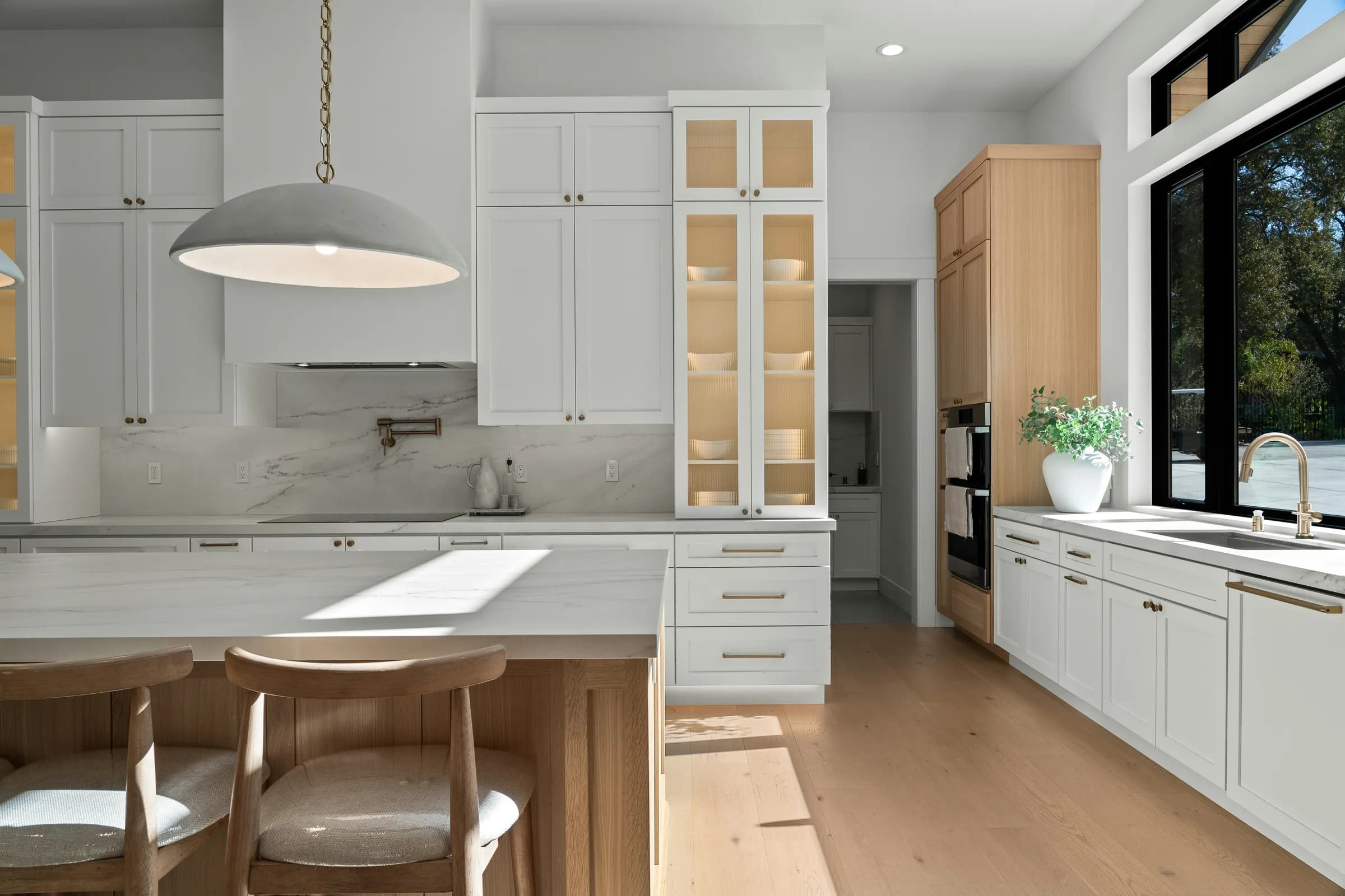 Sunlit kitchen with pale shaker cabinetry and a timber dining table