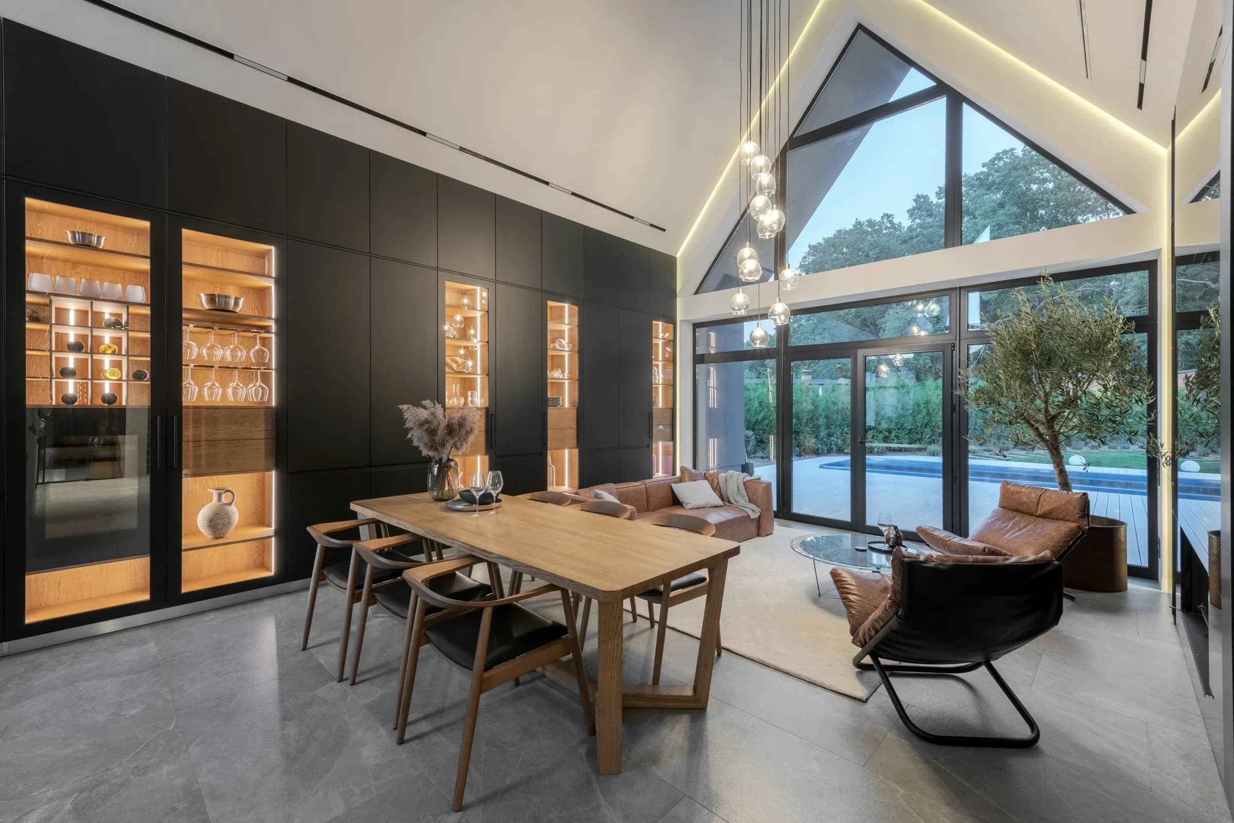 Vaulted dining room at dusk with illuminated cabinetry and garden views